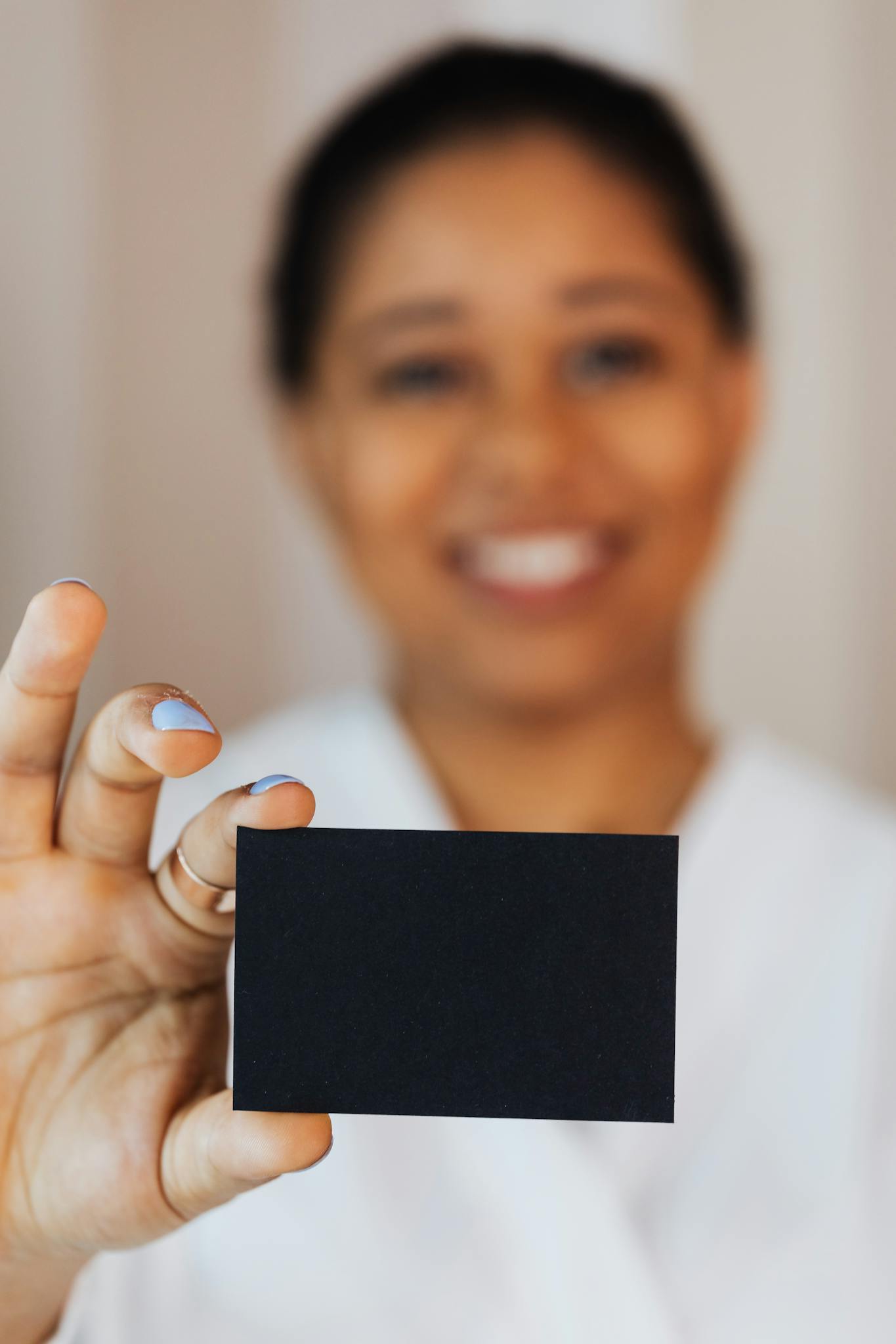 A cheerful woman presents a blank black card, perfect for business or creative use.