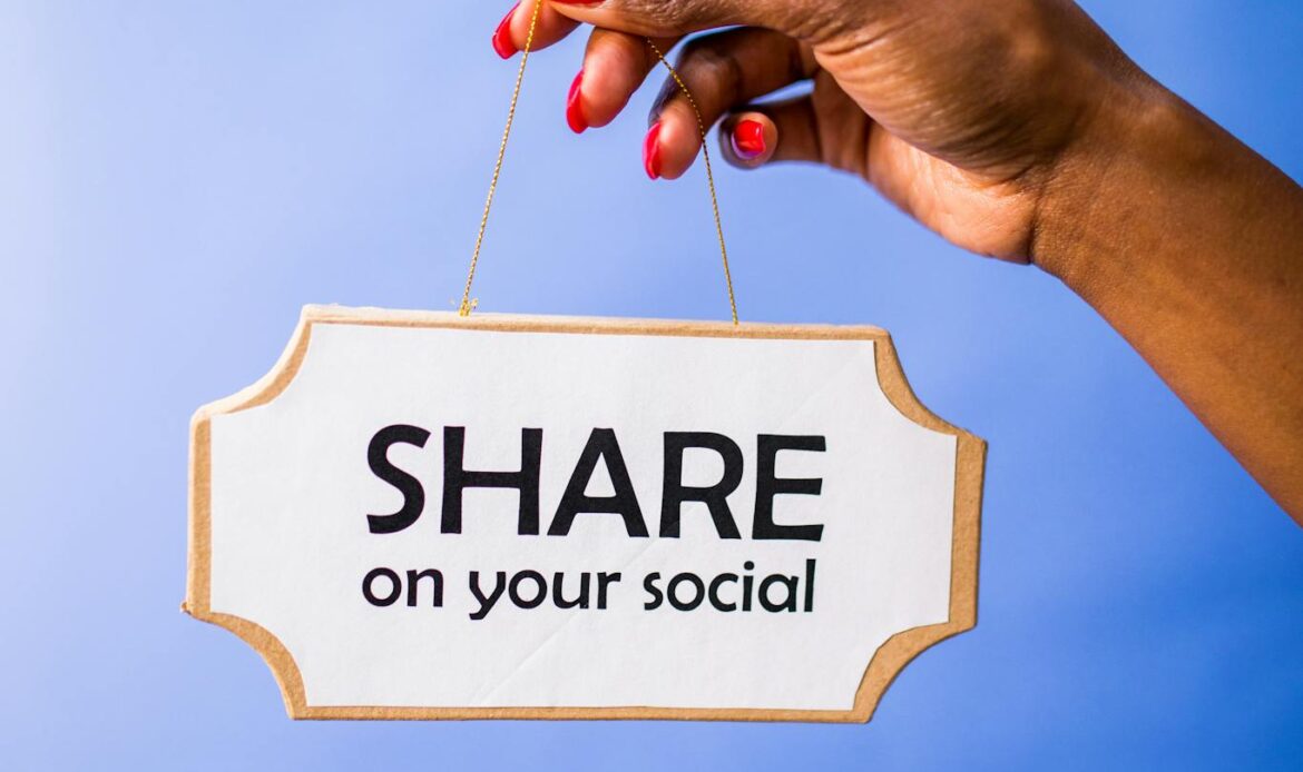 Close-up of a hand holding a 'Share on your social' sign on a vibrant blue backdrop.